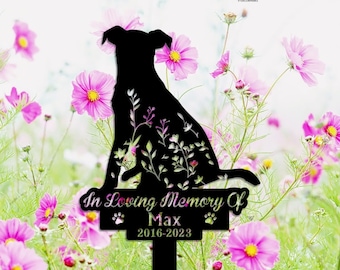 May include: Black metal dog silhouette garden stake with floral accents and the text "In Loving Memory Of Max 2016-2023". The stake is surrounded by pink flowers.