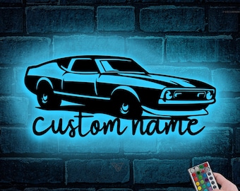 May include: A black silhouette of a classic car with the text "custom name" in a white outline. The car is illuminated with a blue light and a remote control is visible in the bottom right corner.