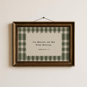 May include: A framed print with a gold-toned wooden frame. The artwork features a green and white gingham pattern border and a central beige rectangle with the text "His Mercies Are New Every Morning. Lamentations 3:23."