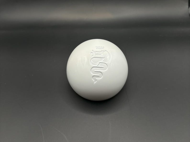 May include: White round gear shift knob with a raised Alfa Romeo logo.