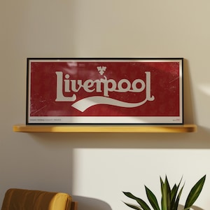 May include: A rectangular framed print featuring a red background with a subtle repeating pattern and the white text Liverpool in a stylised font. The design includes a small white emblem above the text and a white swoosh graphic below.