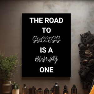 May include: Black and white motivational quote on a canvas print. The quote reads "The road to success is a bumpy one".