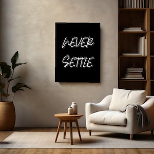 May include: A rectangular black wall art piece featuring the white text NEVER SETTLE in a stylized, layered font. The artwork is displayed on a plain wall above a wooden side table with two small white vases, a white armchair, and a floor lamp.