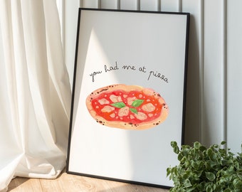 May include: A white framed print with the text "you had me at pizza" in black cursive writing. A watercolor illustration of a pizza with red sauce, cheese, and basil is below the text.
