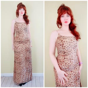 May include: A floor-length, sleeveless dress with a leopard print pattern. The dress features thin spaghetti straps and a fitted bodice that flows into a straight skirt. The color palette includes shades of tan, brown, and black.