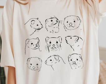 May include: A white t-shirt with a black line drawing of multiple ferret faces. The ferret faces are all different and have a variety of expressions.