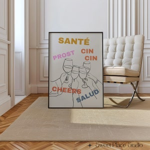 May include: A black framed poster with a white background and a line drawing of four hands holding up wine glasses. The words "Sant&eacute;", "Prost", "Cin Cin", "Cheers", and "Salud" are written in different colours around the glasses.