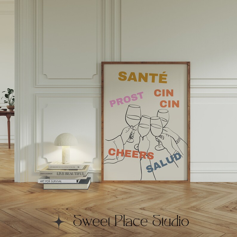 May include: A beige poster with a black line drawing of five hands holding up wine glasses. The words "Sant&eacute;", "Prost", "Cin Cin", "Cheers", and "Salud" are written in different colours around the glasses.
