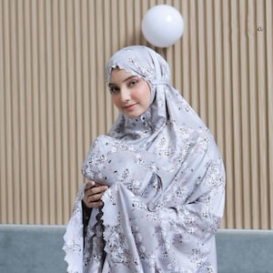 May include: A gray prayer shawl with a floral pattern. The shawl has a lace trim and is folded in half.