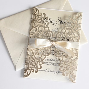 May include: A gold glitter wedding invitation with a white ribbon and a lace design. The invitation reads "Lindsey Stern and Michael Stern" and includes the wedding date, time, and location. The invitation is accompanied by a white envelope.