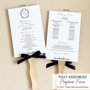 May include: Black and white wedding program fans with a black ribbon bow. The front side of the fan says "Welcome to the wedding of Brittany & Matthew" and the back side lists the wedding party.