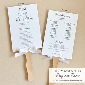 May include: Double-sided wedding program fans with white ribbon bows. The front side features the text "KM" and "Welcome to the wedding of Kim & Mike" with the date "September 19, 2027". The back side features the text "The Wedding Party" and a list of the wedding party members. The fans are 5.5 inches by 8.5 inches.