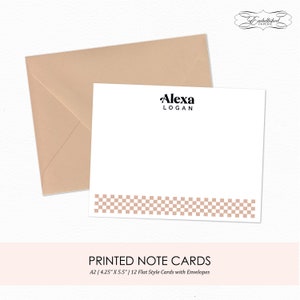 May include: A set of 12 flat style note cards with envelopes. The cards are white with a black and white checkered border. The text "Alexa Logan" is printed in black at the top of the card. The envelopes are a light brown color.