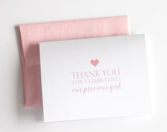 May include: A white thank you card with a pink heart and the text "Thank you for celebrating our precious girl". The card is sitting on a pink envelope.