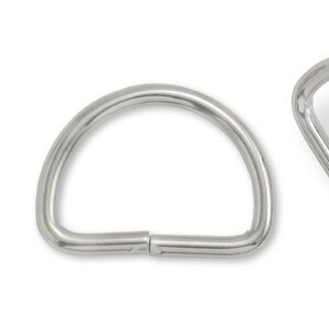 May include: Two silver metal D-rings, each with a smooth, rounded surface. The rings are open and ready to be attached to a project.