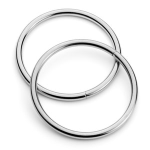 May include: Two silver metal rings, one slightly larger than the other, are stacked on top of each other. The rings are smooth and shiny.