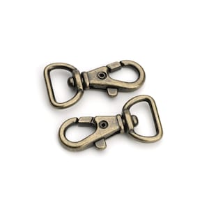 May include: Two antique gold-toned metal swivel clasps with a D-ring on one end and a hook on the other end.