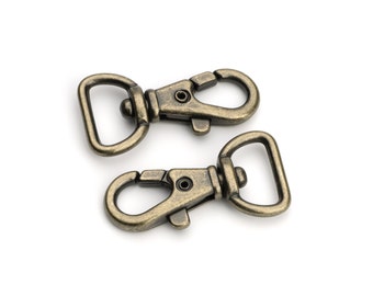 May include: Two antique gold-toned metal swivel clasps with a D-ring on one end and a hook on the other end.