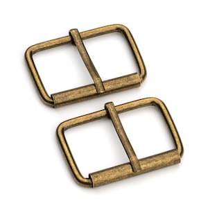 May include: Two antique gold metal belt buckles. The buckles are rectangular with a smooth, slightly textured finish.