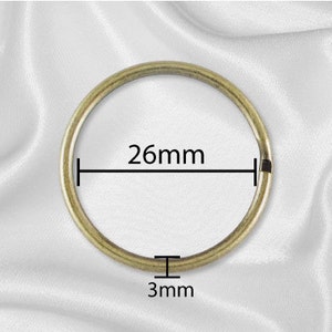 May include: A gold-toned metal ring with a diameter of 26 mm and a thickness of 3 mm.