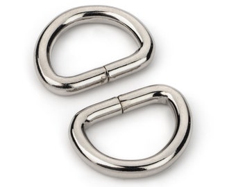 May include: Two silver metal D-rings, also known as key rings, are shown against a white background.