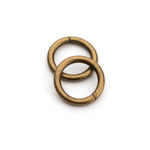 May include: Two gold-toned metal rings, one slightly larger than the other, are interlocked. The rings are smooth and have a slightly worn finish.