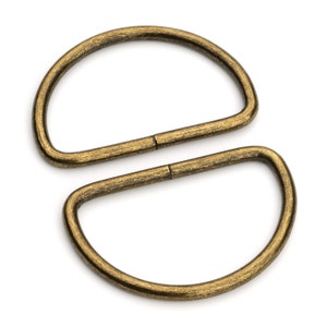 May include: Two antique gold-toned metal D-rings. The rings are connected together.