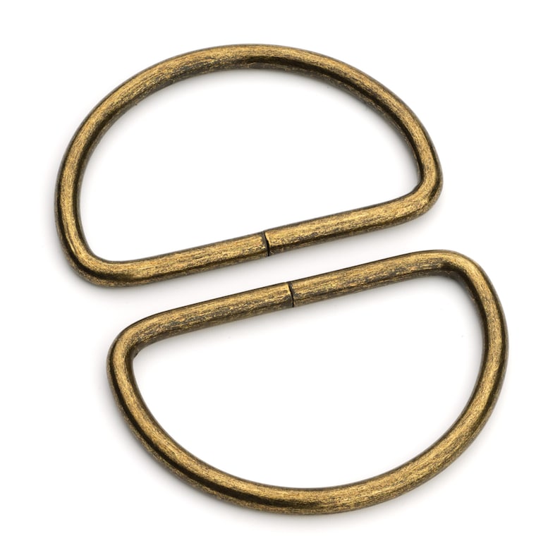May include: Two antique gold-toned metal D-rings. The rings are connected together.