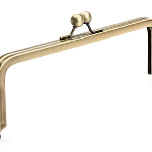 May include: A gold-toned metal purse frame with two round knobs at the top.