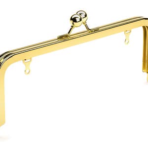 May include: Gold-toned metal purse frame with two round knobs at the top and two D-ring clasps on each side.