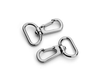 May include: Two silver metal swivel clasps with a rounded opening. The clasps are commonly used for attaching straps or chains to bags, purses, or other accessories.