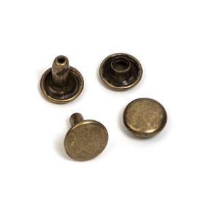 May include: Four antique gold metal rivets with a round head and a post. The rivets are used for attaching fabric or leather.