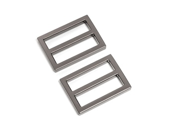 Puede incluir: Dos hebillas deslizantes de metal plateado. Las hebillas son rectangulares con dos ranuras paralelas.