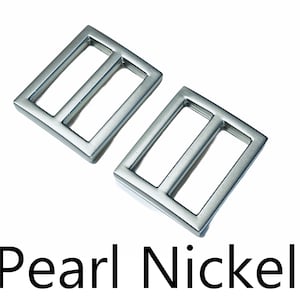 May include: Two silver metal slider buckles, also known as a trigger snap, in a pearl nickel finish.
