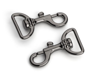 May include: Two gunmetal-colored swivel snap hooks. Each hook has a D-ring, a spring-loaded clasp, and a decorative ribbed section. The hooks are designed for attaching to bags, straps, or other accessories.