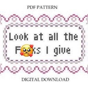 May include: A cross-stitch pattern with a pink and white border. The pattern says "Look at all the F***s I give" with a yellow emoji face with a hand over its mouth and hearts around it.