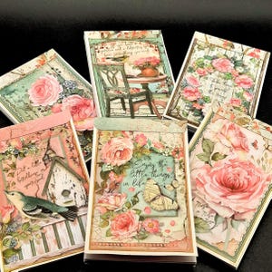 May include: A collection of decorative paper cards with floral and nature-themed designs. Each card features roses, butterflies, and birdhouse illustrations, with text like "Enjoy the little things in life" and "Put a little birdhouse in your soul."