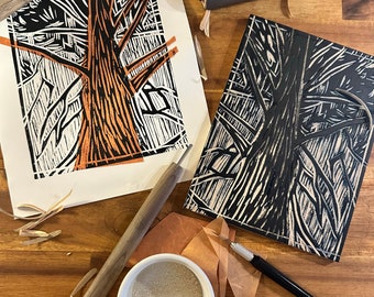 May include: A linocut print of a tree with orange and black ink, alongside the linoleum block, tools, and ink. The print shows a detailed tree design with a textured trunk and branches. The tools include a roller, carving tools, and a small bowl of ink.