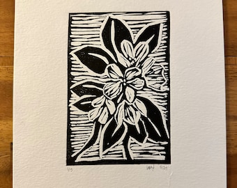 May include: Black and white linocut print of a stylized flower with five petals and leaves. The print is framed by a black border and has the number "1/3" and the text "LMY 5/21" in the bottom corners.