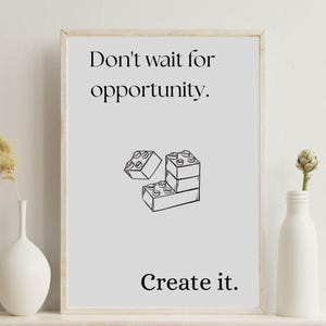May include: A framed print with the text "Don't wait for opportunity. Create it." in black font. The image includes a black and white illustration of toy building blocks. The print is displayed on a white shelf.