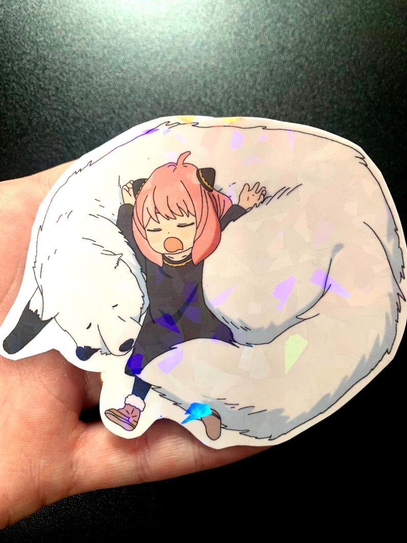 May include: A sticker featuring a cartoon girl with pink hair sleeping on a white furry animal. The sticker has a holographic finish.