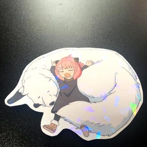 May include: A sticker featuring a cartoon girl with pink hair sleeping on a white furry animal with a holographic finish.