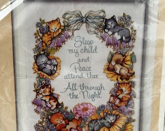May include: A cross-stitch pattern featuring a wreath of sleeping kittens and flowers with the text "Sleep my child and Peace attend thee All through the Night". The pattern is titled "0545 All Through the Night" and is designed by Carol Wynno.