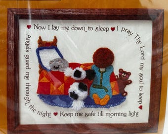 May include: Embroidered picture with a white background and a colorful scene of a child in a bed with a teddy bear and a cat. The text reads "Now I lay me down to sleep I pray The Lord my soul to keep Angels guard me through the night Keep me safe till morning light."