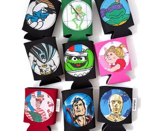 May include: A collection of nine foam beverage insulators featuring circular graphic prints of various pop culture characters including a Smurf, Kermit the Frog, a Teenage Mutant Ninja Turtle, Batman, Oscar the Grouch, a Cabbage Patch doll, Waldo, Superman, and C-3PO.