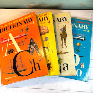Puede incluir: Cuatro diccionarios ilustrados Golden Book vintage. El volumen 1 es naranja, el volumen 2 es amarillo, el volumen 3 es blanquecino y el volumen 4 es azul. Cada libro presenta ilustraciones y texto coloridos.