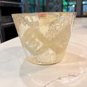 May include: A tapered glass vessel featuring a mercury glass finish with a speckled metallic appearance. The exterior surface is decorated with a repeating opaque white geometric diamond pattern that wraps around the circumference of the container.