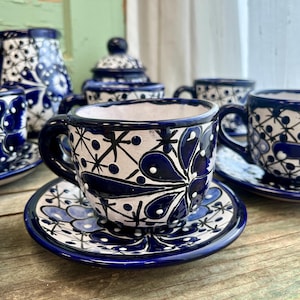 May include: A set of blue and white ceramic teacups and saucers featuring a floral design. The cups and saucers are hand-painted with intricate details.