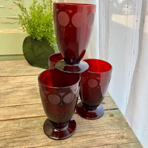 May include: Four red glass tumblers with a geometric pattern. The glasses are stacked on top of each other.