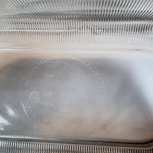 May include: Clear glass rectangular baking dish with a ribbed design on the sides. The text "Microwave Bake" is visible in a circular pattern. The dish is designed for oven and microwave use.